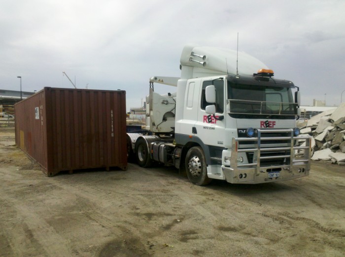 Side loader dropping shipping container off